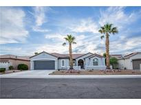 Charming single-story home featuring a well-manicured yard with palm trees and a gray two-car garage at 2099 Mountain City St, Henderson, NV 89052