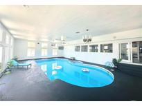 Bright indoor pool area features a blue in-ground pool, lounge chair, and recessed lighting at 2890 Belcastro St, Las Vegas, NV 89117