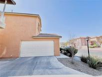 Attached two-car garage with extended driveway and desert landscaping against blue sky at 3542 Harbor Tides St, Las Vegas, NV 89147