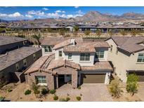 A beautiful two-story home featuring a red tile roof, lush landscaping, and a brick-paved driveway at 365 Malpaso St, Las Vegas, NV 89138