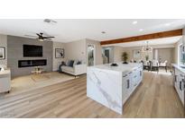 Spacious living room featuring a sleek fireplace, modern fan, and a stylish kitchen island at 356 Gulfport Ct, Las Vegas, NV 89145