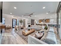 Bright open-concept living room featuring hardwood floors, a large sectional couch, and seamless access to the modern kitchen at 365 Crown Mesa Ave, Las Vegas, NV 89138