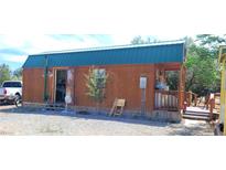 Cozy cabin with wood siding, teal roof, and open porch offering rustic charm at 1590 Landmark Ave, Pahrump, NV 89060