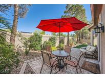 Inviting backyard patio area featuring a red umbrella, outdoor furniture set, and a beautifully stamped concrete patio at 1609 Hidden Spring Dr, Las Vegas, NV 89117