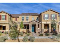 Beautiful townhome with stone accents, inviting landscaping and a stylish teal-colored front door at 2878 Via Firenze, Henderson, NV 89044