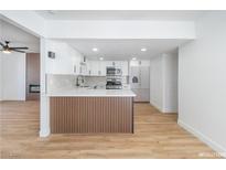 Bright kitchen boasts white cabinets, stainless steel appliances, and stylish wood accents for a modern aesthetic at 3459 One Nation Ave, Las Vegas, NV 89121