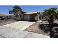Street view of a distressed single-story house with desert landscaping, a two-car garage, and significant damage needing repair at 6723 Oak Valley Dr, Las Vegas, NV 89103