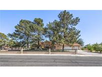 Charming single-story home with mature trees, a terra cotta roof and a low-walled front yard at 7460 Buckskin Ave, Las Vegas, NV 89129