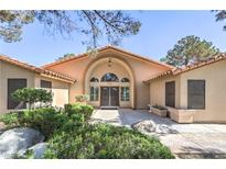 Inviting home featuring a grand entrance with a beautiful arched doorway and manicured landscaping at 7460 Buckskin Ave, Las Vegas, NV 89129