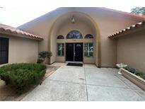 Inviting front entrance featuring double doors, arched entryway, and well-maintained landscaping at 7460 Buckskin Ave, Las Vegas, NV 89129