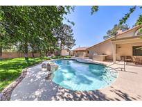 Backyard swimming pool with a rock waterfall feature and surrounding patio at 7460 Buckskin Ave, Las Vegas, NV 89129