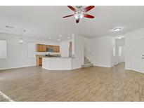 Open-concept living area features hardwood floors and a view into the kitchen with breakfast bar at 9535 Stills Way, Las Vegas, NV 89148
