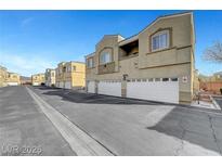 Street view showing attached garages and a row of two-story townhomes on a clear day at 6320 Desert Leaf St # 101, North Las Vegas, NV 89081