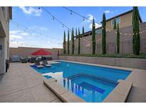 Inviting backyard pool and spa area with lounge chairs and beautiful string lights at 9654 Starfish Reef Way, Las Vegas, NV 89178