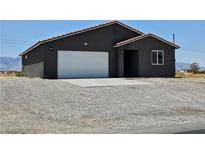 Charming single-story home with a white garage door and low maintenance desert landscaping at 1870 Upland Ave, Pahrump, NV 89048
