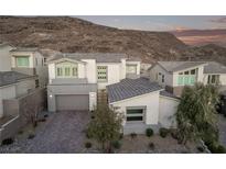 Inviting two-story home with a gray and white color scheme, mountain views, and a well-manicured front yard at 30 Hilltop Crest St, Henderson, NV 89011