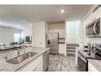 Modern kitchen features stainless steel appliances, gray countertop island, and open floor plan to the living room at 12728 Feathersong St, Henderson, NV 89044