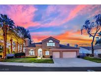 Charming two-story home with well-manicured lawn and mature palm trees, set against a vibrant sunset sky at 1984 Troon Dr, Henderson, NV 89074