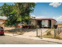 Quaint single-story home featuring a chain-link fenced yard and a mature shade tree in front at 704 Kings Ave, North Las Vegas, NV 89030
