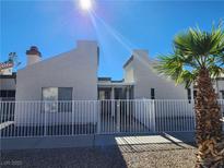 Modern home exterior with white fence and desert landscaping under a bright blue sky at 2106 Pebble Creek Ln, Laughlin, NV 89029