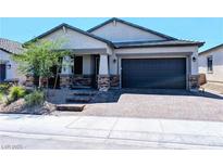 Charming single-story home featuring a two-car garage, stone accents, and a well-manicured front yard at 6021 Vivanco St, North Las Vegas, NV 89081