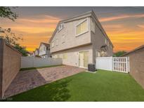 A fenced backyard with faux grass, a brick patio, and the home's rear entrance at 9312 Straw Hays St # 103, Las Vegas, NV 89178