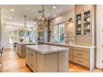 Bright eat-in kitchen with double islands, wood floors, stainless steel appliances, and modern lighting fixtures at 1235 Panini Dr, Henderson, NV 89052