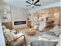 Bright living room with fireplace, ceiling fan, modern furnishings, and open access to a gourmet kitchen at 1624 Ravanusa Dr, Henderson, NV 89052