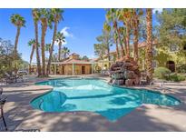 Resort style pool and sunning area featuring palm trees and decorative rock waterfall at 7950 W Flamingo Rd # 1003, Las Vegas, NV 89147