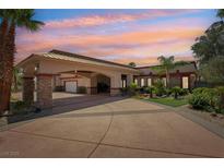 Majestic home with portico entry, circular driveway, and mature landscaping against a vibrant sunset sky at 9111 W Stephen Ave, Las Vegas, NV 89149