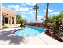 Inviting backyard pool with rock features and mature palms, perfect for relaxation at 1016 Eaglewood Dr, Las Vegas, NV 89144