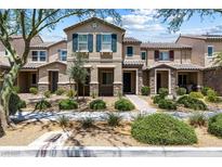 Inviting townhouse featuring a well-manicured lawn and charming facade with stone accents and desert landscaping at 3188 Via Da Vinci, Henderson, NV 89044
