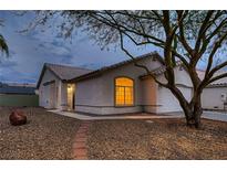 Charming single-story home with a well-manicured front yard and warm exterior lighting at dusk at 3426 Side Saddle Ct, North Las Vegas, NV 89032