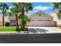 Charming single-story home featuring a two-car garage, lush lawn and mature palm trees at 9205 Desert Village Ave, Las Vegas, NV 89147