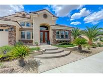 Inviting stucco home featuring stone accents, a curved entry, and lush landscaping with palm trees at 2168 Big Bar Dr, Henderson, NV 89052