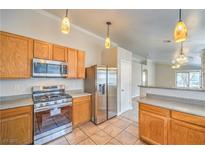 Well-lit kitchen featuring stainless steel appliances, wooden cabinetry, and tiled flooring at 2177 Hidden Ranch Ter, Henderson, NV 89052