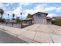 Inviting gray two-story home featuring a well-kept yard, decorative fence and mature palms at 3400 Sioux Way, Las Vegas, NV 89169