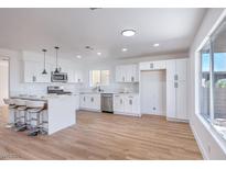 Bright kitchen boasts white cabinets, stainless steel appliances, and a large island with bar stool seating at 6420 Rosemount Ave, Las Vegas, NV 89156