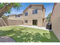 A backyard with a wall fence, artificial grass, a concrete patio, and a sliding glass door into the home at 9105 White Eyes Ave, Las Vegas, NV 89143