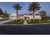 Stunning single-story home with a circular driveway, lush landscaping, and mature palm trees at 11926 Port Labelle Dr, Las Vegas, NV 89141
