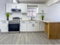 This remodeled kitchen features stainless steel appliances, white cabinets, and a charming wood-accented peninsula at 1608 E Mcdonald Ave, North Las Vegas, NV 89030