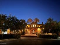 Elegant home at night featuring an ornate iron gate and lush landscaping at 1800 Amarone Way, Henderson, NV 89012