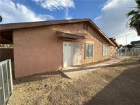 Exterior view of a one-story home, featuring stucco siding, a front door, a fenced yard, and simple landscaping at 3936 Rive Gauche St, Las Vegas, NV 89115