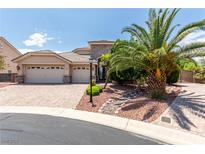 Inviting single-story home featuring a three-car garage, stone accents, and mature palm tree landscaping at 6779 Rainstorm Ridge Ave, Las Vegas, NV 89131