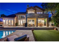 Elegant backyard with a sparkling pool, stone patio, and outdoor seating area at dusk at 7988 Pinnacle Peak Ave, Las Vegas, NV 89113