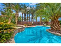 Inviting pool area surrounded by lush landscaping and swaying palm trees, creating a serene backyard oasis at 5992 Quintillion Ave, Las Vegas, NV 89122