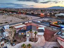 Expansive single story home featuring palm trees, solar panels, and red rock landscaping at dusk at 7477 Ullom Dr, Las Vegas, NV 89139