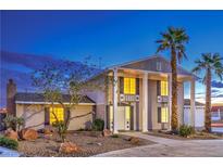 Charming two-story home showcasing stately pillars, a well-manicured lawn, and elegant front entrance at 7477 Ullom Dr, Las Vegas, NV 89139