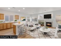 Open-concept living room with a modern fireplace, a breakfast bar, and light hardwood flooring at 7936 Pinnochio Ave, Las Vegas, NV 89131