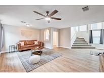 Bright living room features modern ceiling fan, neutral paint, stylish decor and carpeted stairs at 9328 Jumpin Juniper Ave, Las Vegas, NV 89129